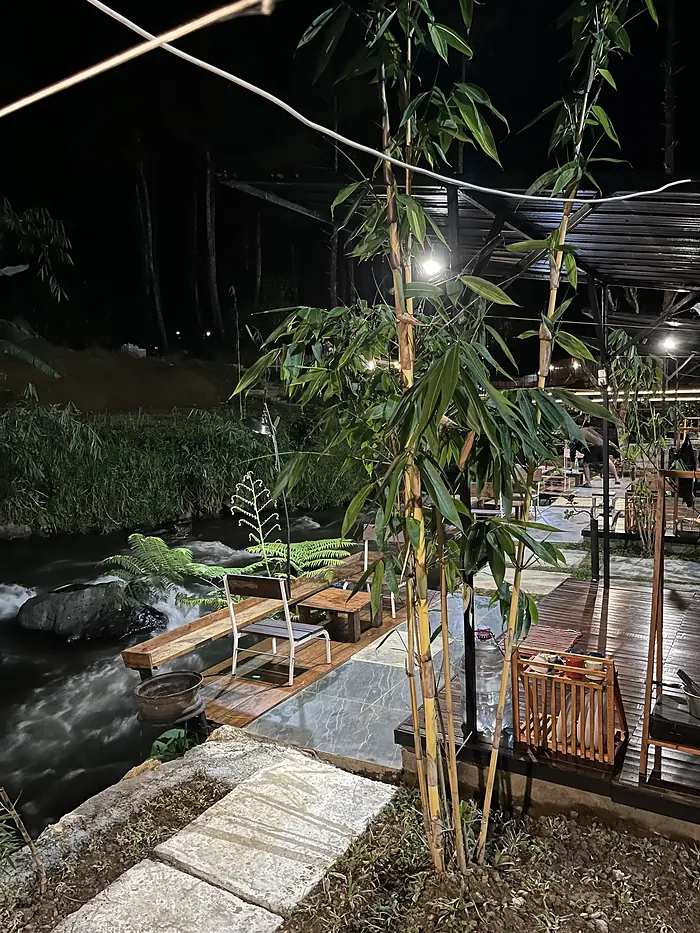 Jalan setapak dan deck kayu di tepi sungai yang disinari lampu