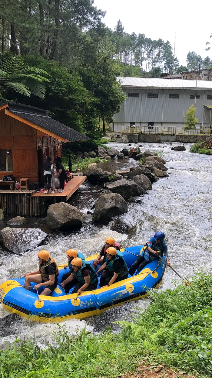 Perahu rafting berisi tamu bersiap di tepi sungai