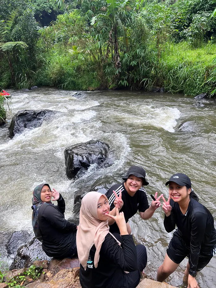 Tamu duduk bersama di bebatuan tepi sungai
